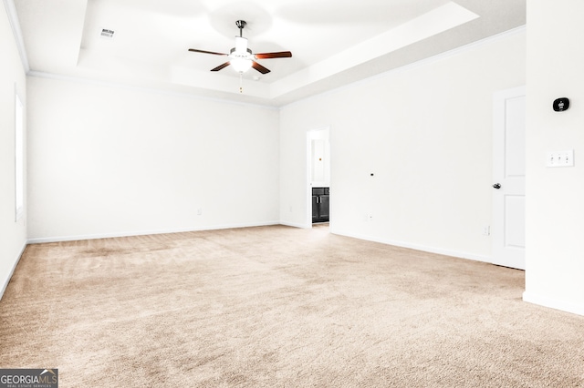 spare room with carpet, ceiling fan, ornamental molding, and a tray ceiling