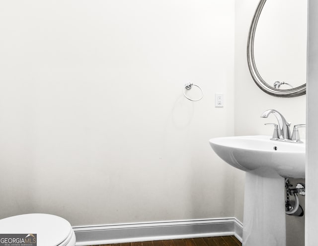 bathroom with wood-type flooring, a baseboard radiator, and toilet