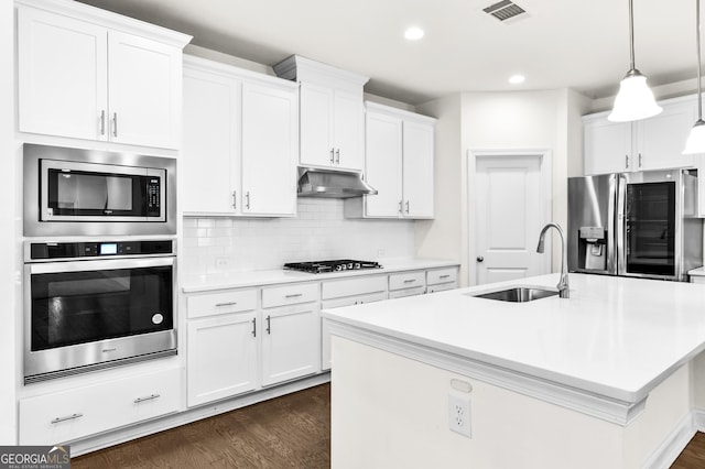 kitchen featuring a kitchen island with sink, white cabinets, sink, hanging light fixtures, and stainless steel appliances