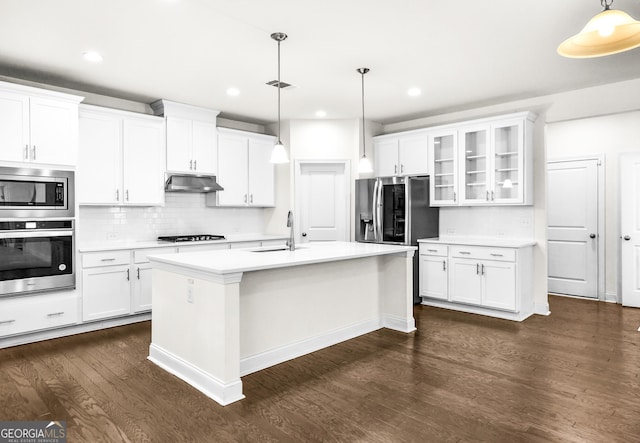 kitchen featuring appliances with stainless steel finishes, tasteful backsplash, pendant lighting, white cabinets, and an island with sink