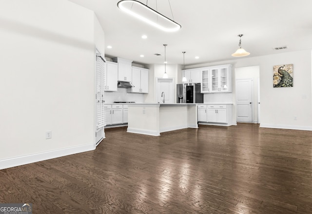 kitchen featuring tasteful backsplash, stainless steel refrigerator with ice dispenser, an island with sink, pendant lighting, and white cabinets