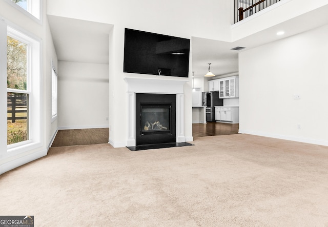 unfurnished living room featuring dark carpet and a high ceiling