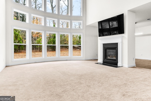 unfurnished living room with a towering ceiling and carpet floors