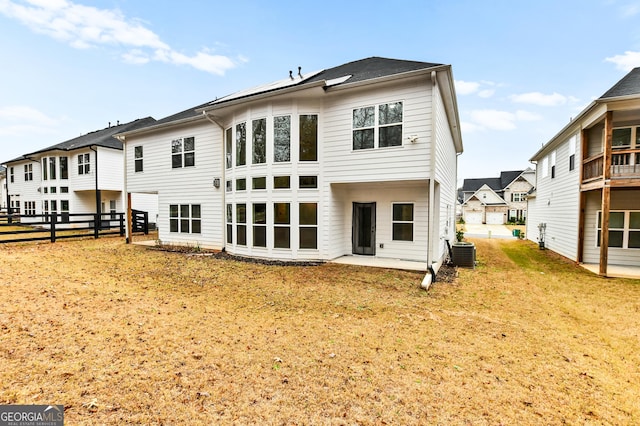 rear view of house with central AC, a patio area, and a yard