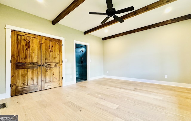 unfurnished bedroom with ceiling fan, beam ceiling, ensuite bathroom, and light hardwood / wood-style flooring