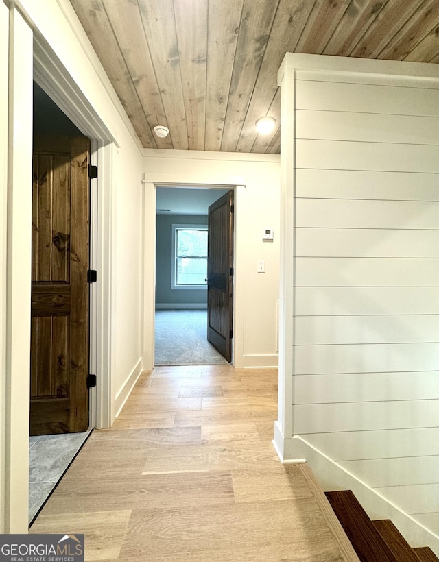 hallway featuring light wood-type flooring and wooden ceiling