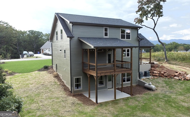 rear view of property with a lawn, a wooden deck, cooling unit, and a patio