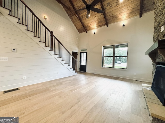 unfurnished living room with ceiling fan, high vaulted ceiling, wooden ceiling, a fireplace, and light hardwood / wood-style floors