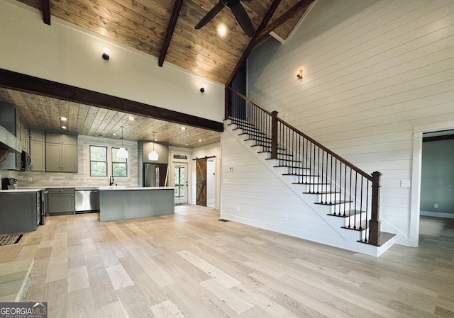 unfurnished living room featuring a barn door, light hardwood / wood-style flooring, high vaulted ceiling, and wood ceiling