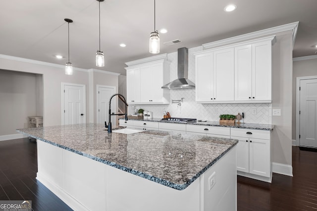 kitchen featuring white cabinets, wall chimney exhaust hood, sink, and a large island with sink