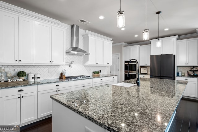 kitchen featuring appliances with stainless steel finishes, white cabinetry, a large island, and wall chimney range hood