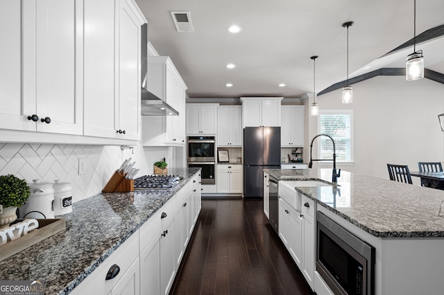 kitchen with backsplash, a kitchen island with sink, dark hardwood / wood-style floors, decorative light fixtures, and stainless steel appliances