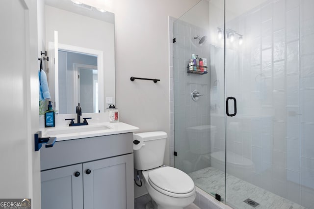 bathroom featuring a shower with door, vanity, and toilet