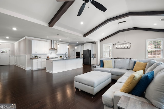 living room featuring ceiling fan with notable chandelier, lofted ceiling with beams, sink, and dark wood-type flooring