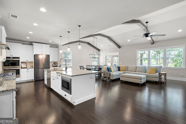 kitchen featuring pendant lighting, stainless steel appliances, white cabinetry, and an island with sink