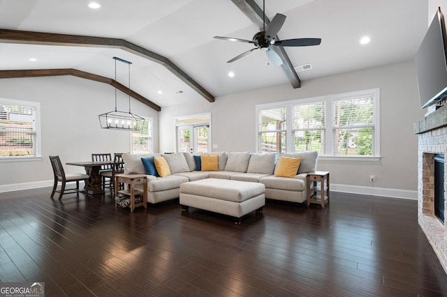 living room featuring vaulted ceiling with beams, dark hardwood / wood-style flooring, a fireplace, and ceiling fan with notable chandelier