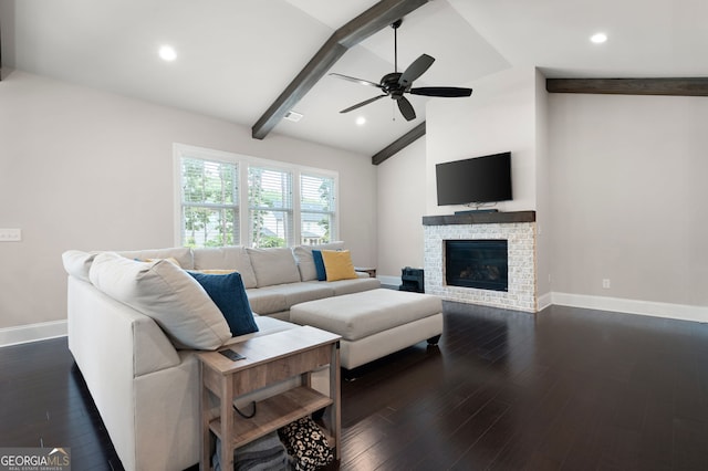 living room featuring vaulted ceiling with beams, ceiling fan, a stone fireplace, and dark wood-type flooring