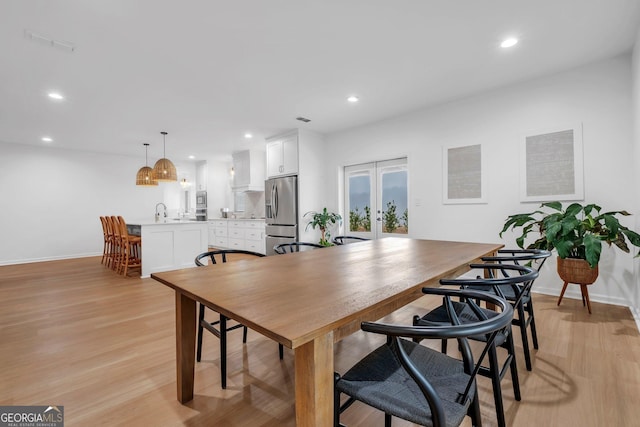 dining room featuring sink, french doors, and light wood-type flooring