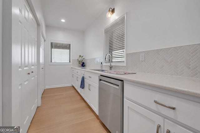 kitchen featuring stainless steel dishwasher, a healthy amount of sunlight, white cabinets, and tasteful backsplash