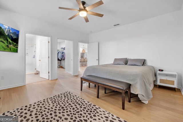 bedroom featuring light wood-type flooring, a walk in closet, connected bathroom, and a closet