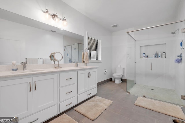 bathroom featuring tile patterned floors, vanity, toilet, and a shower with door