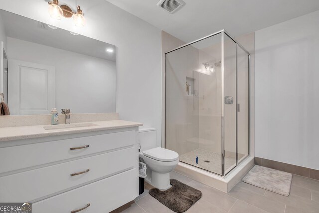 bathroom featuring tile patterned flooring, vanity, a shower with shower door, and toilet