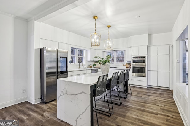 kitchen featuring white cabinetry, sink, stainless steel appliances, pendant lighting, and a kitchen island