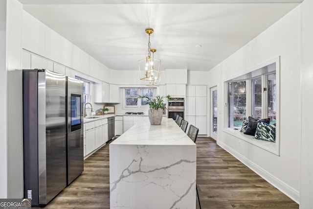 kitchen with a center island, sink, stainless steel appliances, pendant lighting, and white cabinets