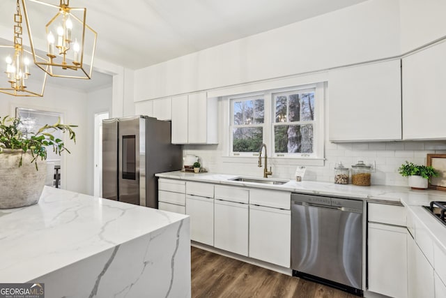 kitchen featuring sink, stainless steel appliances, light stone counters, a notable chandelier, and white cabinets