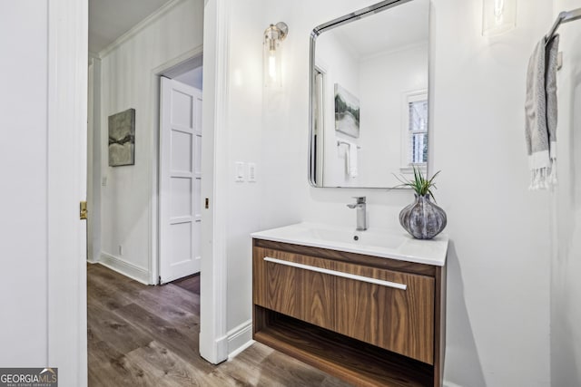 bathroom featuring vanity, ornamental molding, and hardwood / wood-style flooring