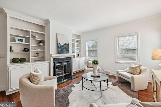 living room with built in shelves, dark hardwood / wood-style flooring, a premium fireplace, and ornamental molding