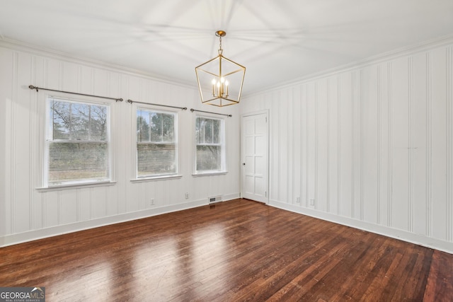 empty room with dark hardwood / wood-style floors, crown molding, and a chandelier