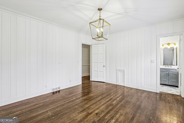 spare room with crown molding, dark hardwood / wood-style flooring, sink, and a notable chandelier