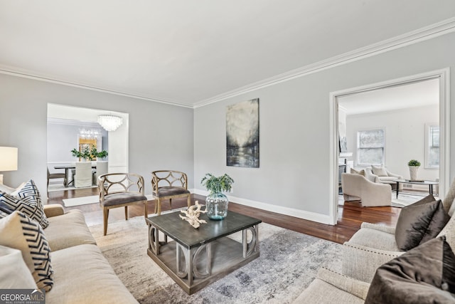 living room with hardwood / wood-style flooring, a notable chandelier, a healthy amount of sunlight, and crown molding