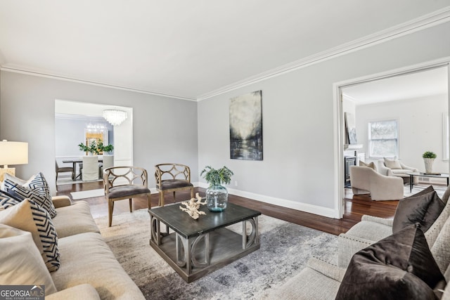 living room with hardwood / wood-style floors, ornamental molding, and a notable chandelier