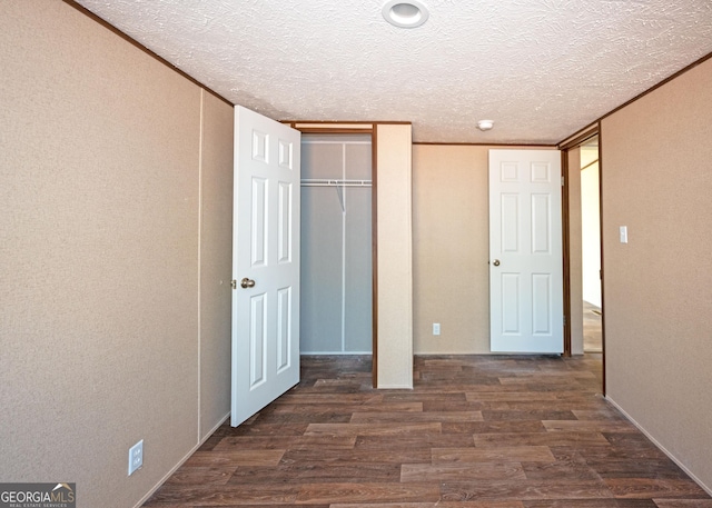 unfurnished bedroom with dark wood-type flooring and a textured ceiling