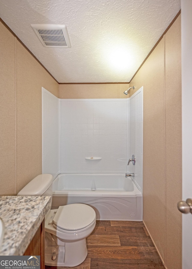 full bathroom with tub / shower combination, hardwood / wood-style floors, a textured ceiling, toilet, and vanity