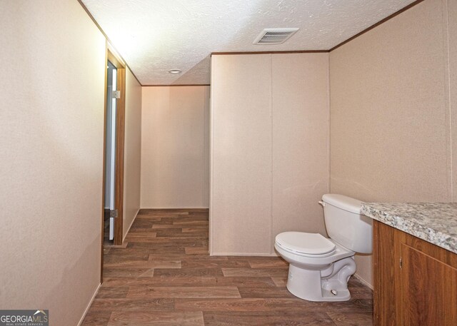 bathroom featuring a textured ceiling, vanity, hardwood / wood-style flooring, and toilet