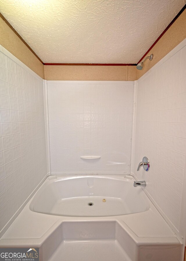 bathroom featuring shower / bathing tub combination, a textured ceiling, and ornamental molding