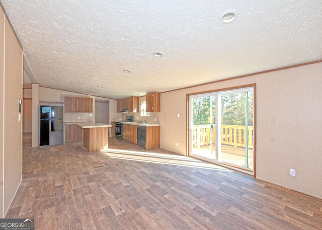 kitchen featuring a textured ceiling, vaulted ceiling, dark wood-type flooring, black appliances, and a kitchen island