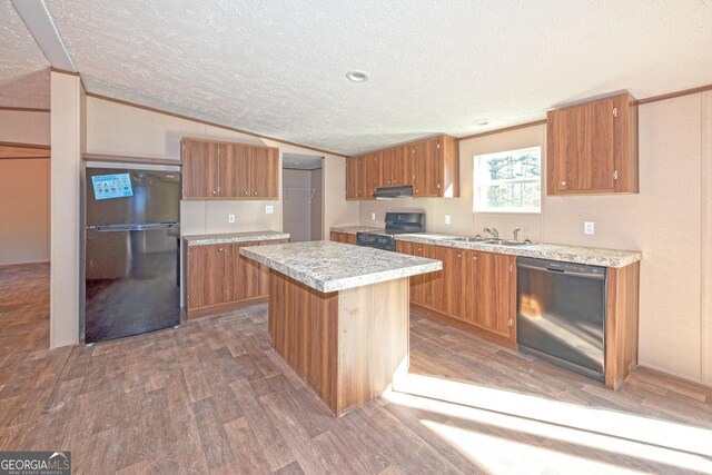 kitchen with a textured ceiling, a center island, black appliances, and vaulted ceiling