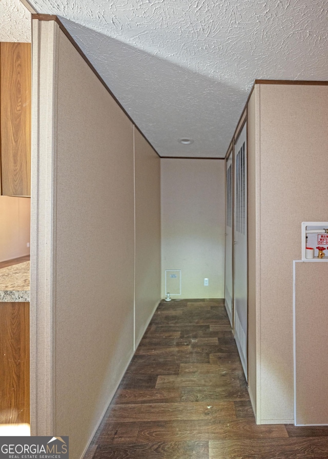 hallway featuring a textured ceiling, dark hardwood / wood-style flooring, and ornamental molding