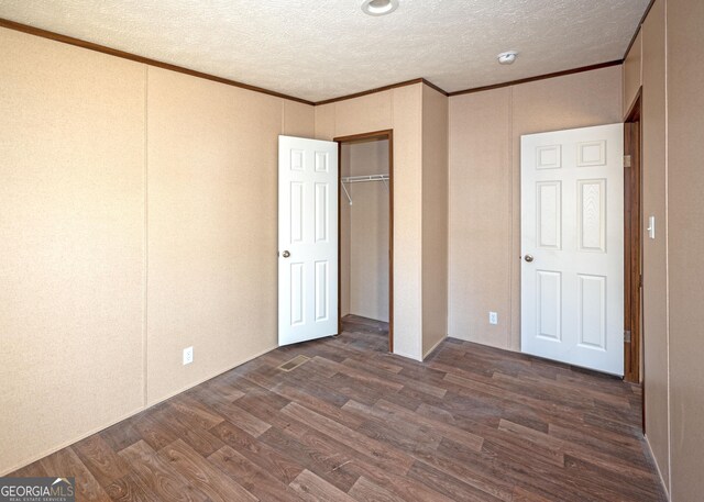 unfurnished bedroom with a textured ceiling, dark hardwood / wood-style flooring, and ornamental molding