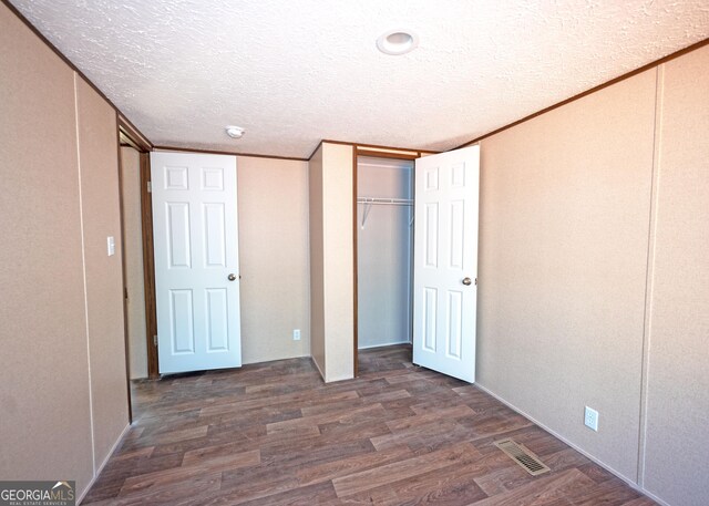 unfurnished bedroom featuring dark wood-type flooring, a textured ceiling, and ornamental molding