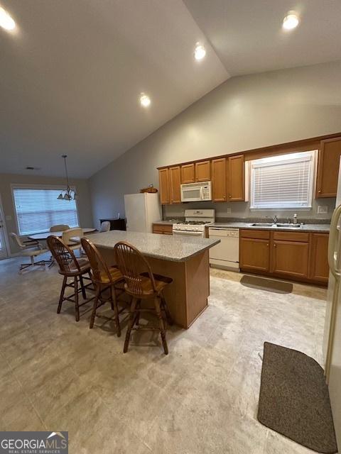 kitchen featuring a kitchen island, light countertops, brown cabinets, white appliances, and a sink