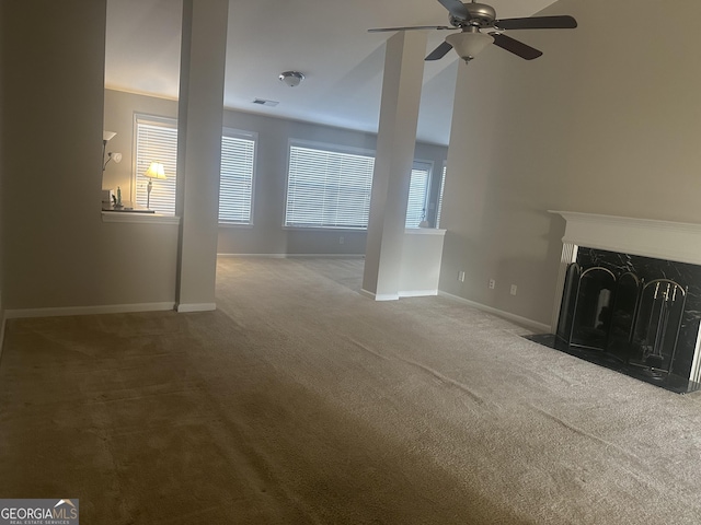 unfurnished living room with visible vents, baseboards, carpet, a premium fireplace, and a ceiling fan