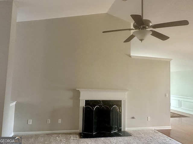 interior details with a decorative wall, a high end fireplace, and ceiling fan