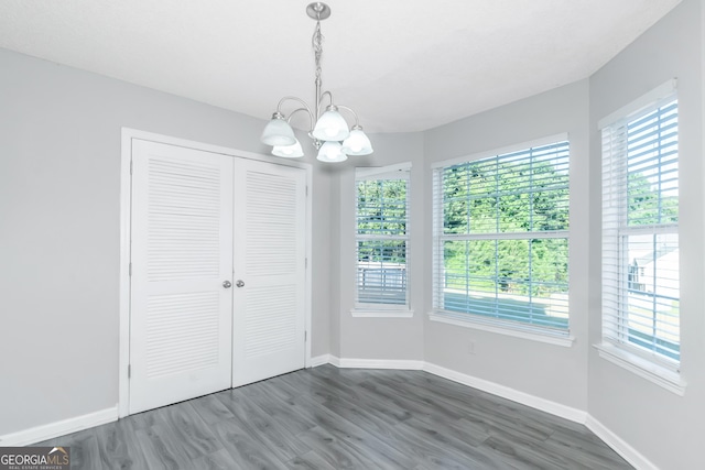 unfurnished bedroom with a closet, dark hardwood / wood-style flooring, and a notable chandelier