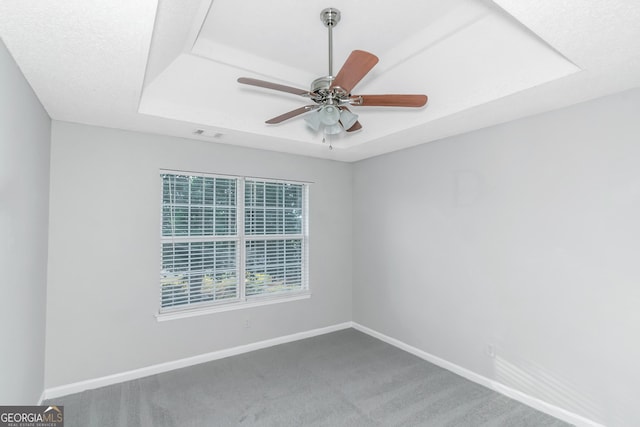 unfurnished room with ceiling fan, a raised ceiling, and carpet floors