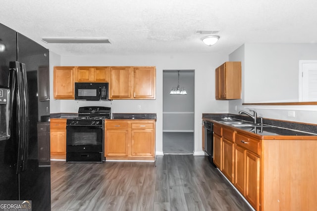 kitchen featuring a textured ceiling, dark wood-type flooring, sink, black appliances, and hanging light fixtures